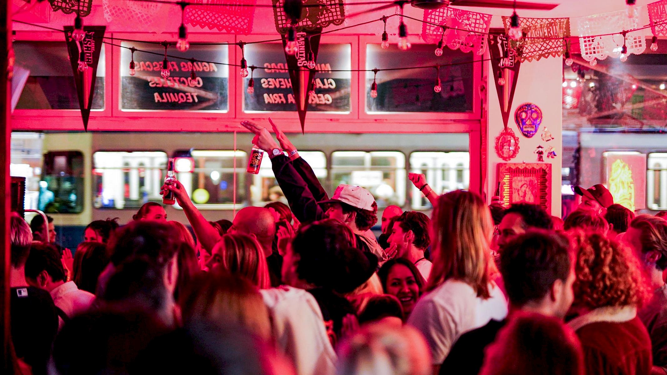 Crowd celebrates with drinks in hand, vibrant colors, enjoying good vibes with El Tony Mate.